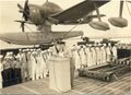 Экипаж тяжелого крейсера USS Los Angeles (CA-135) слушает речь начальства на фоне Curtiss SC-1 Seahawk.