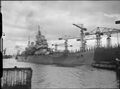 HMS Howe движется вниз по реке мимо верфи где был построен в Глазго.
