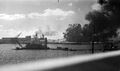 Вид на военно-морскую верфь Перл-Харбора с острова Форд, с земснарядом посередине, 7 декабря 1941 г. Слева - надстройки и мачты линкора USS Pennsylvania, в центре горят эсминцы USS Cassin и USS Downes, справа горит взорвавшийся эсминец USS Shaw.